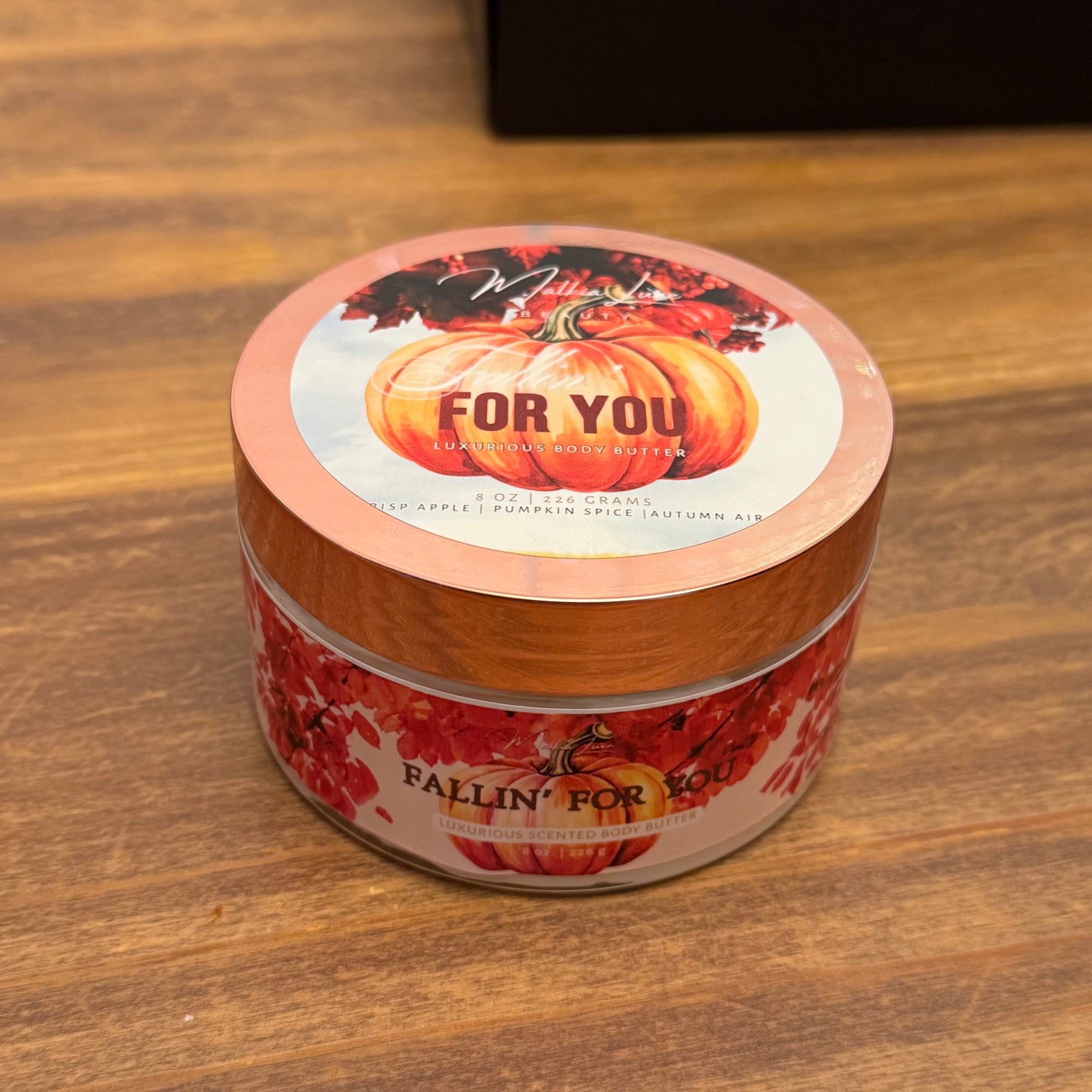 Jar of pumpkin apple body butter with decorative label on a wooden surface