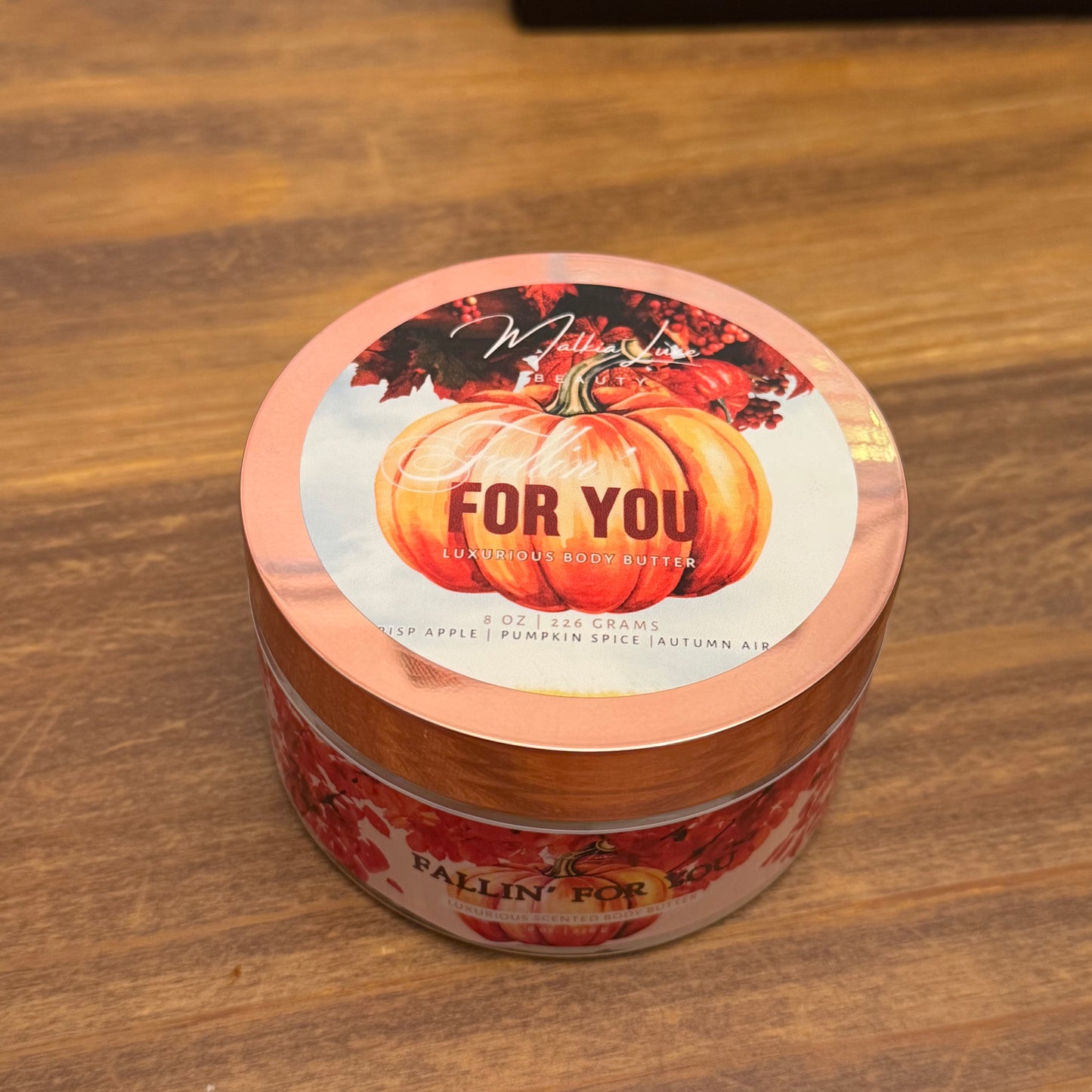 Jar of body butter with pumpkin design on a wooden surface
