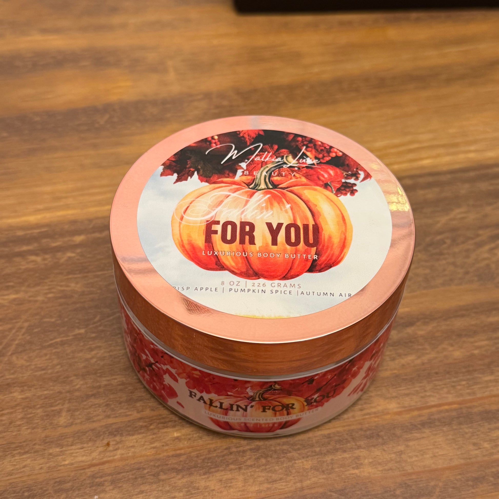 Jar of body butter with pumpkin design on a wooden surface